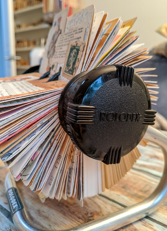 A rotary Rolodex file with collaged cards
